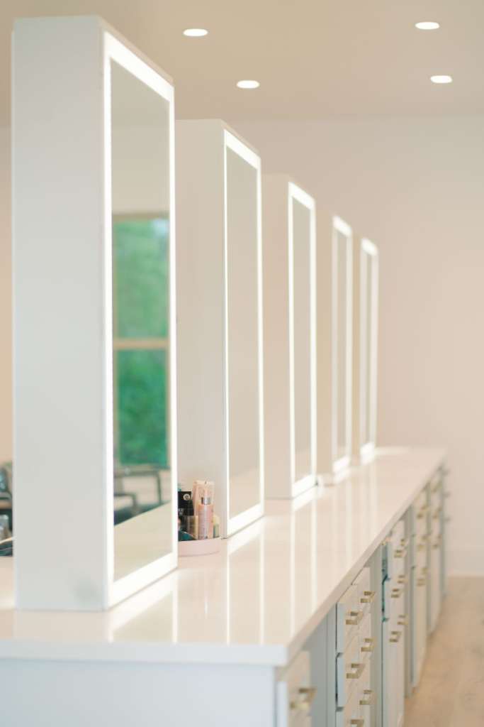 Top salon near Madisonville, LA. A clean, high-angle view of a white salon vanity station featuring a sequence of tall, rectangular mirrors with integrated LED border lighting.